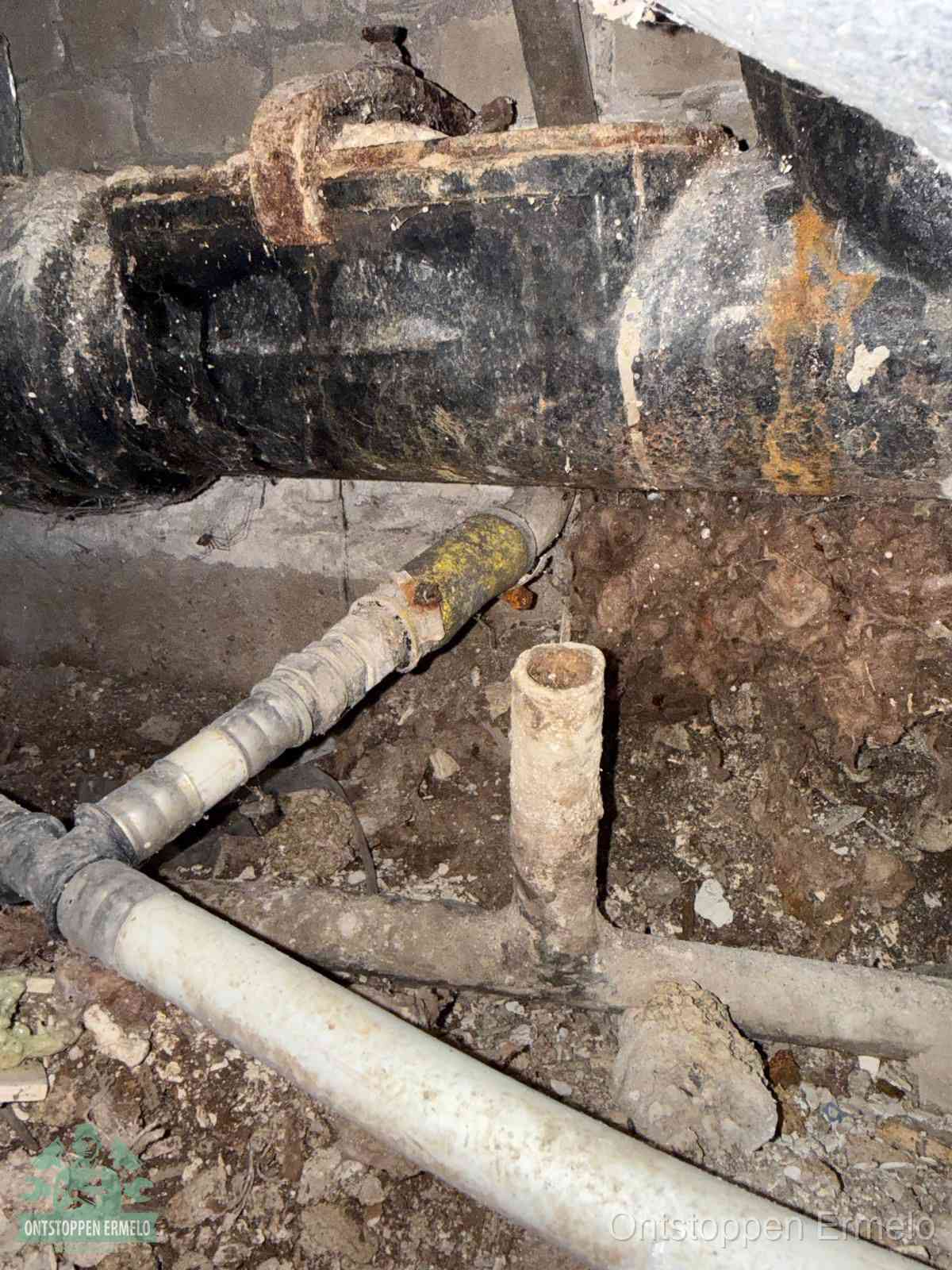 Een oude hoofdrioolbuis met roest- en kalkaanslag in een kruipruimte, oorzaak van terugkerende structurele rioolproblemen in Ermelo