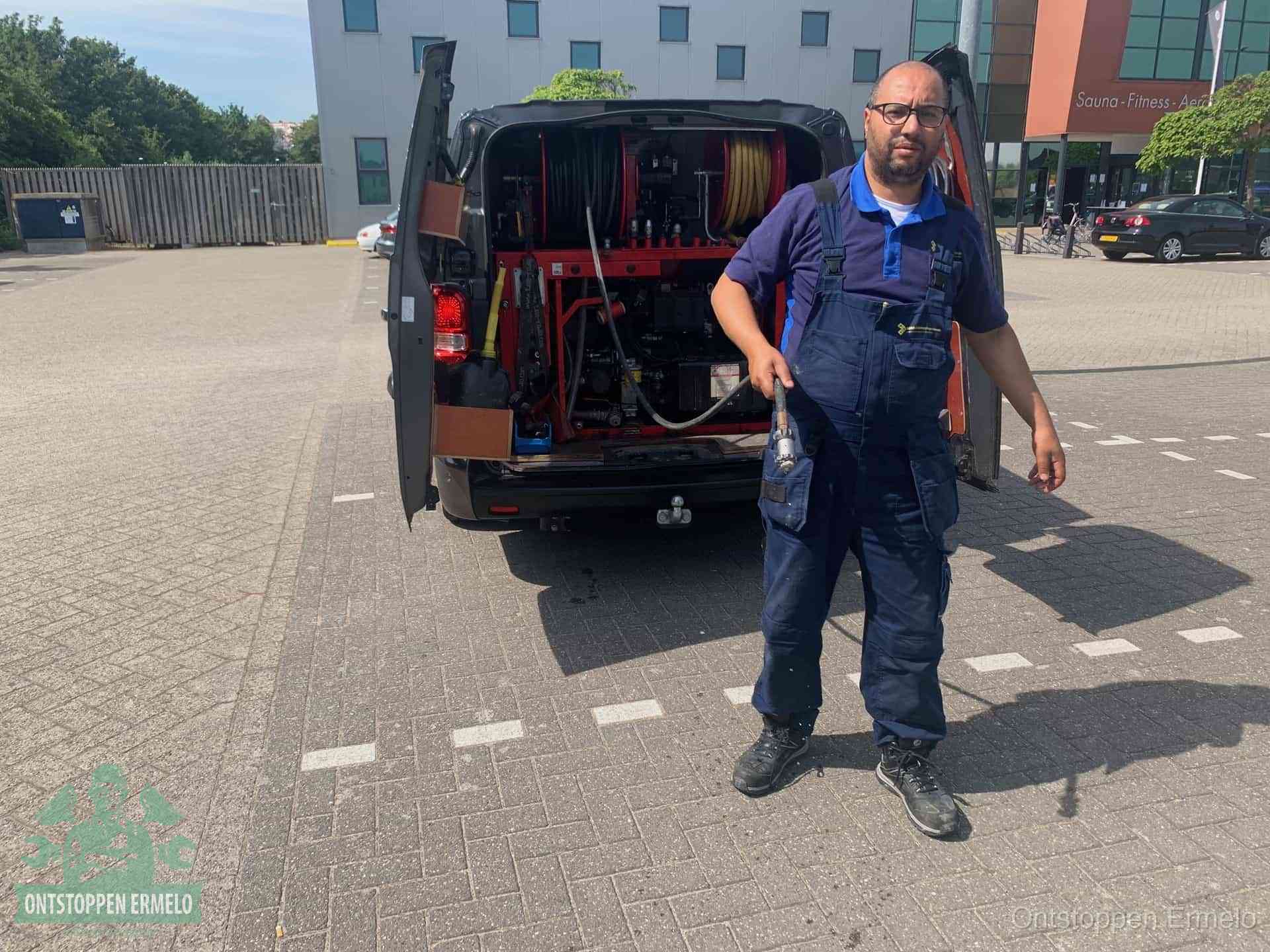 Een monteur bij zijn bestelbus met een hogedruk- en rioolreinigingsunit, klaar om de oorzaak van terugkerende wc-verstoppingen aan te pakken in Ermelo