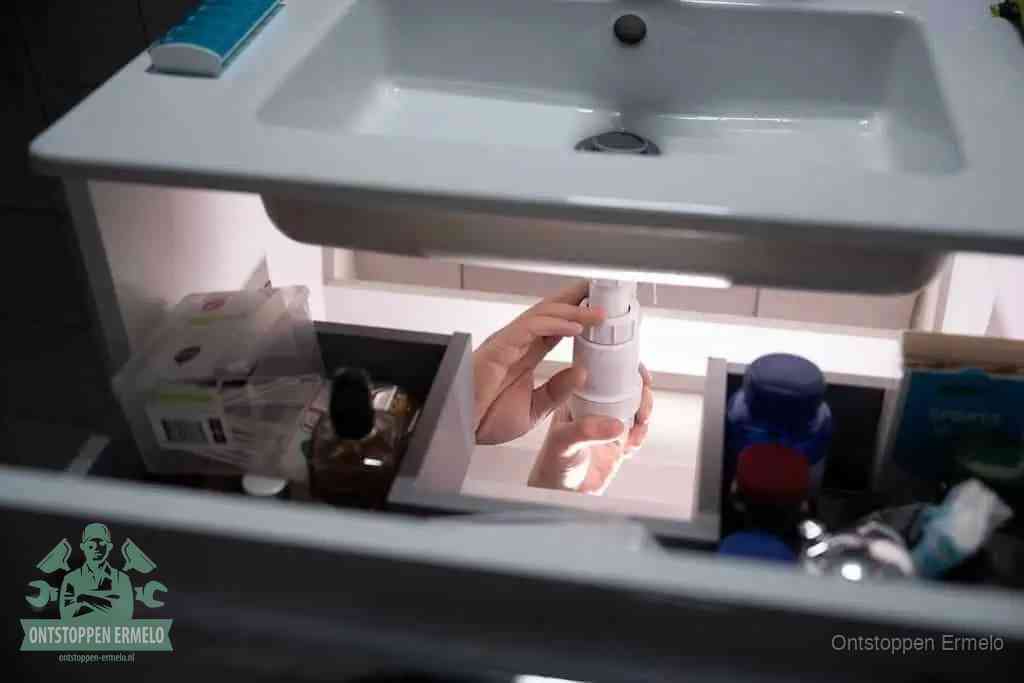 Een pompfles met zeep boven een wastafel in de toiletruimte, de warm water en afwasmiddel-methode om de wc te ontstoppen in Ermelo