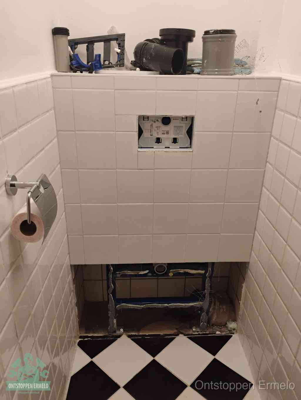 Een toiletruimte waar het hangtoilet en de inbouwreservoir-onderdelen zijn vrijgelegd voor onderhoud, periodiek nazicht voorkomt een wc-verstopping in Ermelo