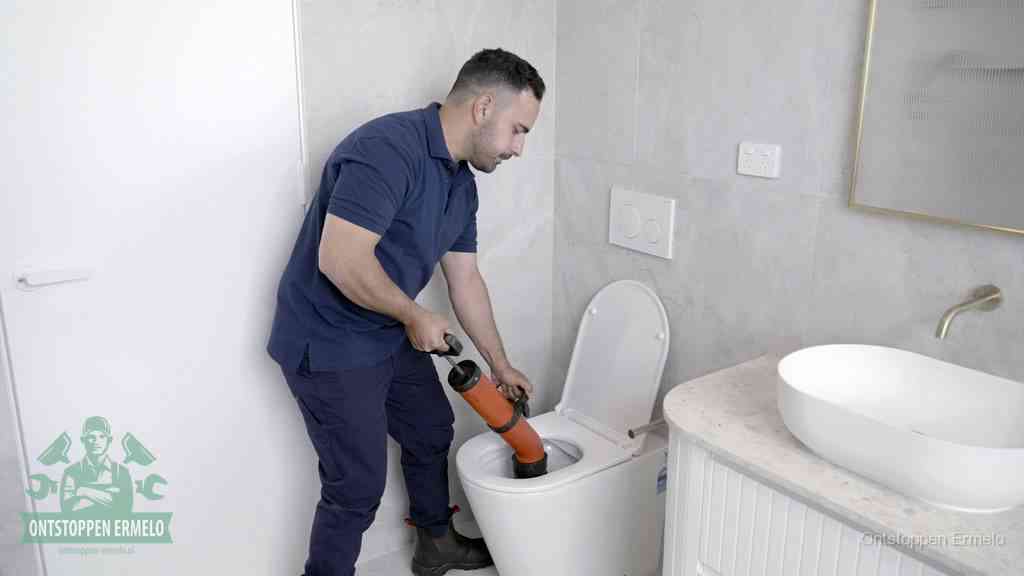 Een monteur gebruikt een handmatige perspomp (toiletontstopper) op een wandcloset tijdens het professioneel wc ontstoppen in Ermelo